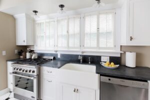 White inset kitchen cabinets with dark countertop and window shutter blinds