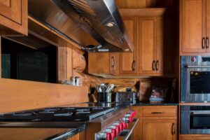 Stainless steel stove, range hood and double ovens in wood tone kitchen