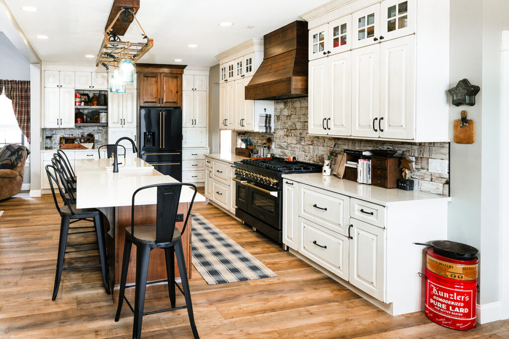 White weathered kitchen cabinets with long island and wood hood above stove