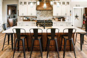 Long brown wood island with 4 metal stools