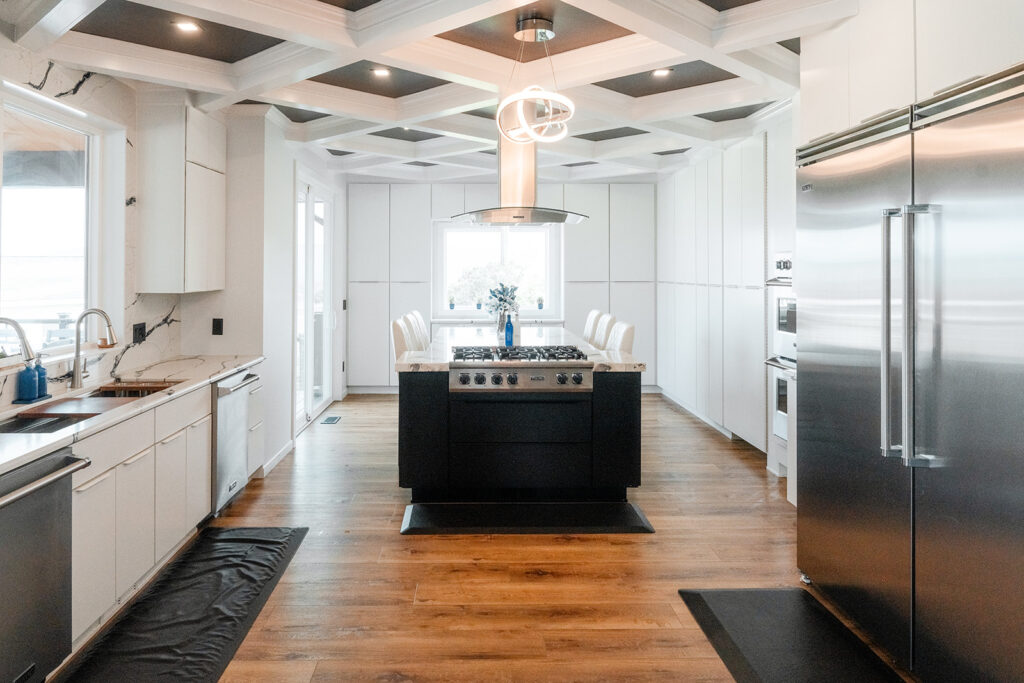 Wide view of black and white kitchen with center island and floor to ceiling storage